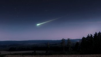 Das Foto zeigt einen Sternenhimmel mit einer hell erleuchteten Sternschnuppe