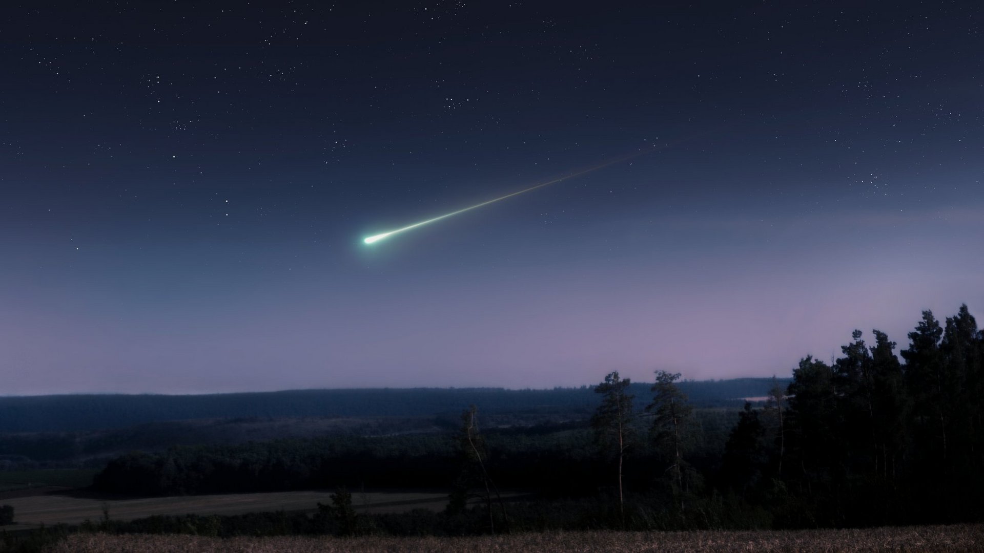 Das Foto zeigt einen Sternenhimmel mit einer hell erleuchteten Sternschnuppe