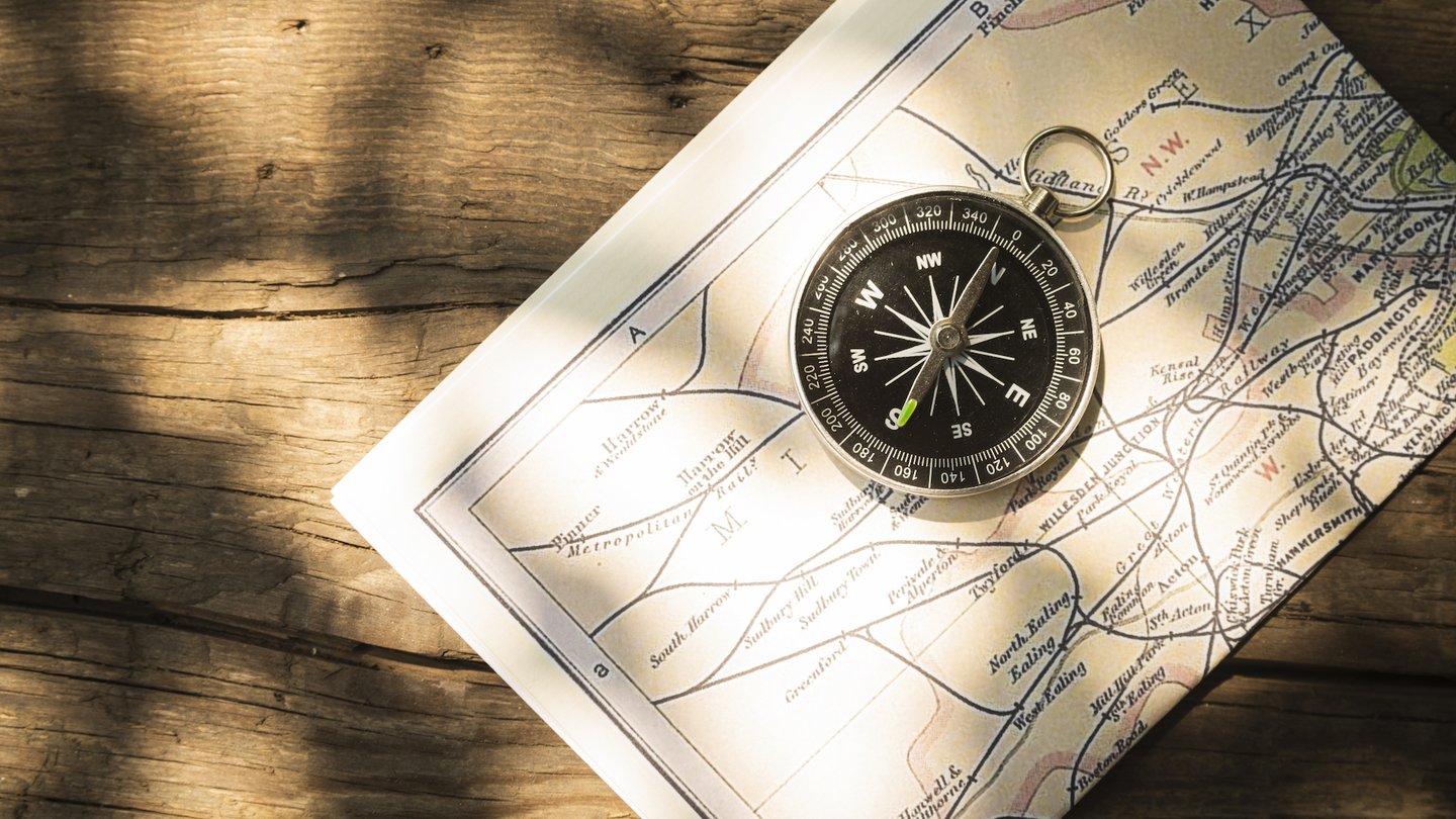 Das Foto zeigt eine Landkarte mit einem Kompass auf hölzernem Untergrund.