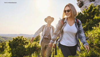 Das Foto zeigt ein junges Paar, das gemeinsam draußen im Freien in den Bergen wandert.