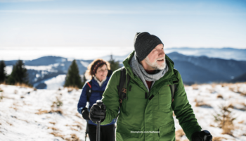 Das Foto zeigt ein Senioren-Ehepaar bei einer Winterwanderung in den Bergen.