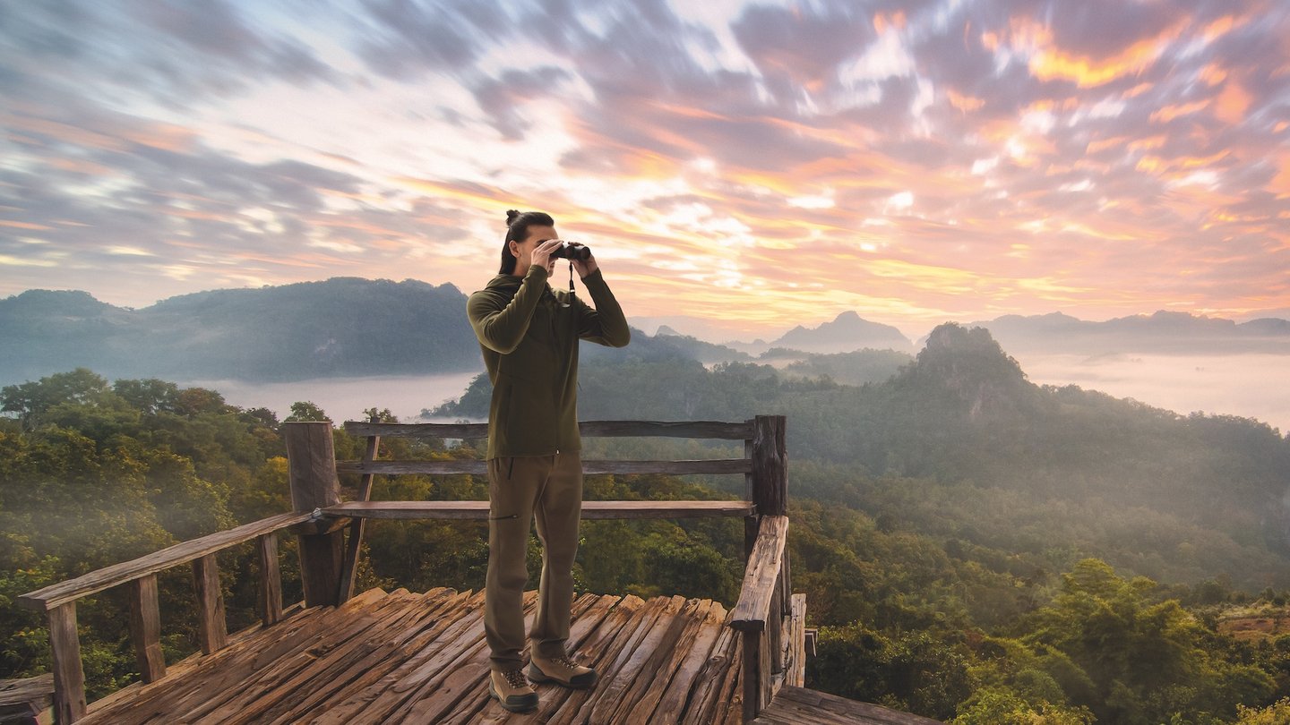 Beobachter mit farlux APO Fernglas genießt Panorama bei Sonnenaufgang