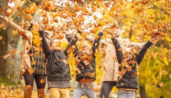 Familie wirft im Herbst gefallene Blätter durch die Luft