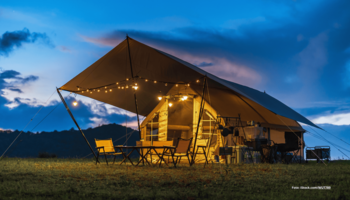 Das Foto zeigt ein Glamping-Zelt mit Lichterkette vor der untergehenden Sonne.