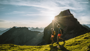 Das Bild zeigt zwei Wanderer in den Bergen bei Sonnenschein