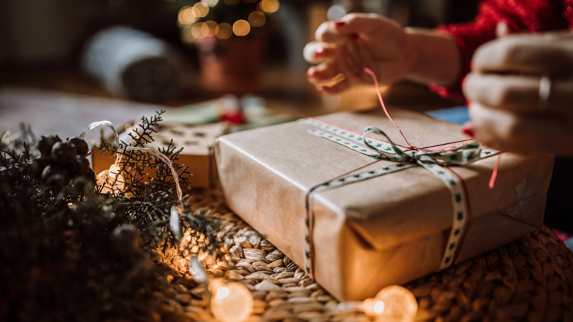 Das Foto zeigt eine Frau, die Weihnachtsgeschenke im Wohnzimmer verpackt.