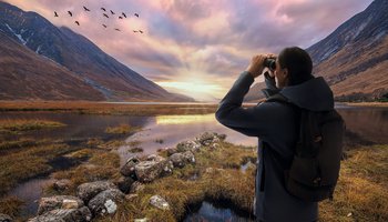 Das Foto zeigt eine Person, die den Himmel mit einem Fernglas beobachtet.