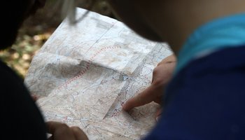Das Foto zeigt zwei Personen, die eine Landkarte lesen.