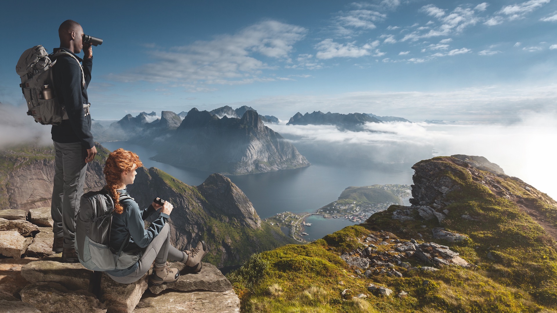 Das Foto zeigt einen Mann und eine Frau, die durch ein Fernglas eine schöne Berglandschaft beobachten.